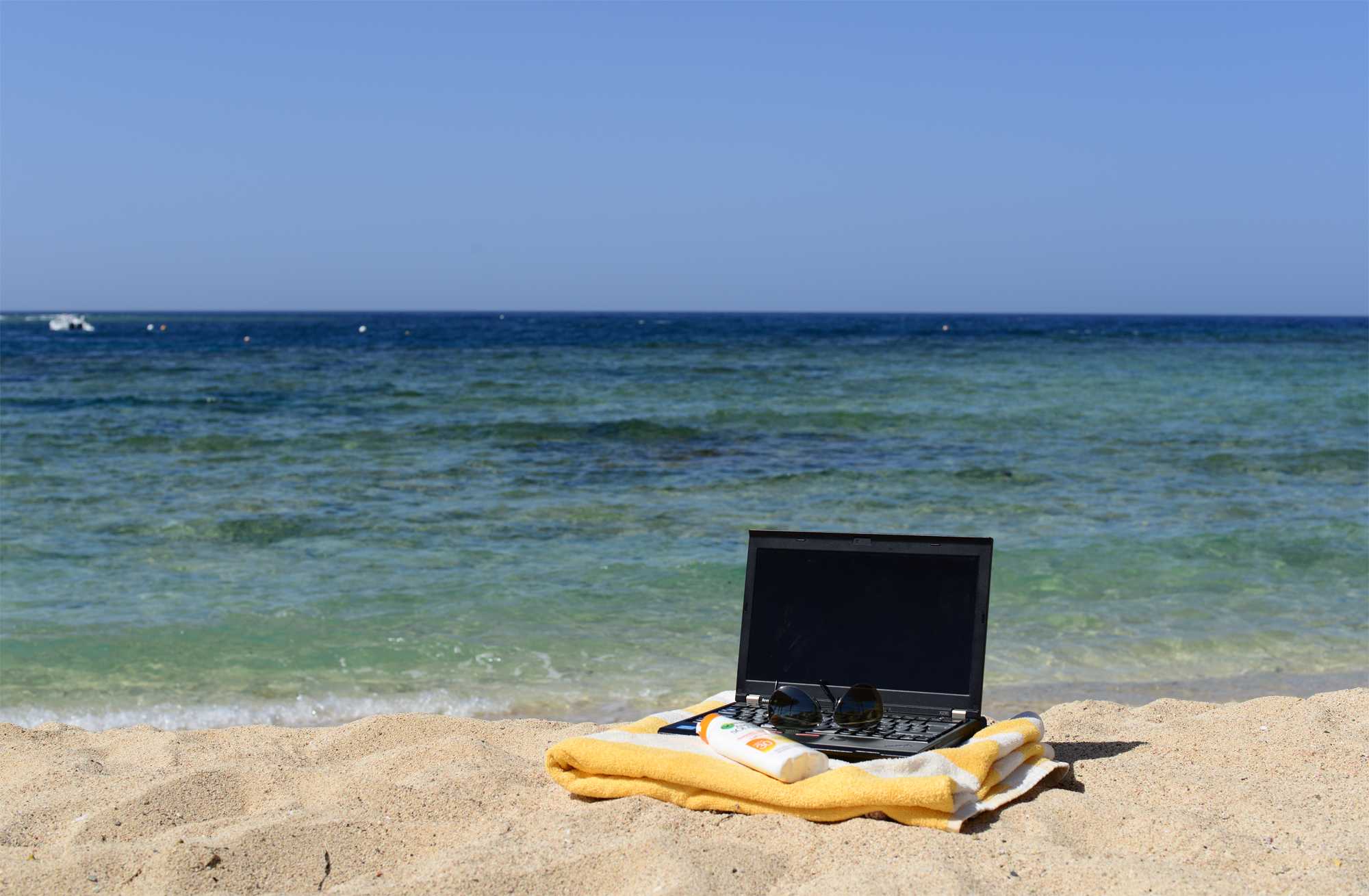 During vacation. С ноутбуком на пляже. С ноутбуком на море. Море пляж ноутбук. Ноутбук на песке.